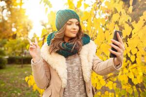 giovane ragazza prende un' autoscatto su il sfondi autunno bellissimo le foglie. foto