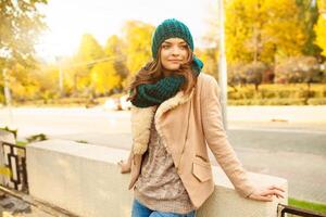 un' bellissimo giovane ragazza passeggiate attraverso il autunno parco su il sfondo di brillantemente colorato le foglie foto