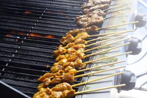 asiatico cucina, Malaysia pollo satay cucinando su un' caldo carbone griglia. foto