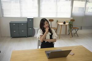 un' preoccupato giapponese donna di a distanza opera nel il piccolo ufficio foto