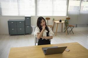 un' preoccupato giapponese donna di a distanza opera nel il piccolo ufficio foto