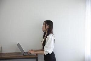 un' giapponese donna controllo smartphone di a distanza opera nel il casa ufficio foto