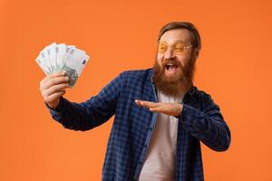 dai capelli rossi barbuto uomo nel occhiali da sole Saluti Tenere Euro banconote, studio foto