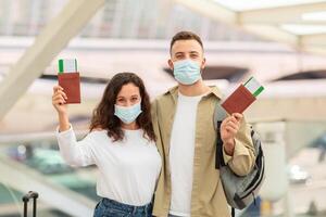 giovane europeo coppia indossare medico maschere nel aeroporto Tenere passaporti e Biglietti foto