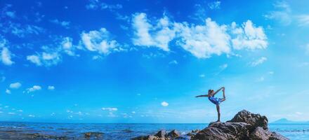 le donne asiatiche si rilassano durante le vacanze. viaggiare rilassati. gioca se lo yoga. sugli scogli in riva al mare. in estate. Tailandia foto