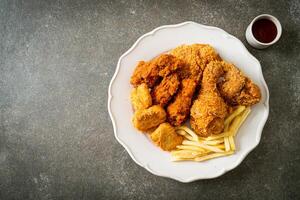 pollo fritto con patatine fritte e pepite sul piatto foto