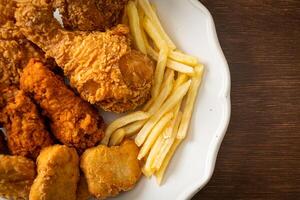 pollo fritto con patatine fritte e pepite sul piatto foto