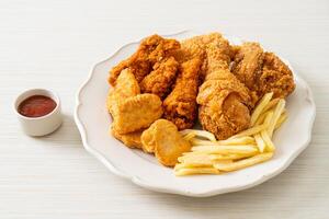 pollo fritto con patatine fritte e pepite sul piatto foto