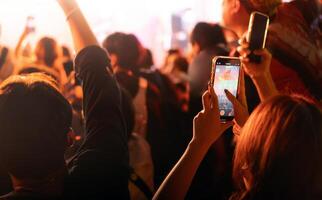 persone Tenere inteligente Telefono e registrazione e Fotografare nel concerto , silhouette di mani con mobile , evento sfondo concetto foto