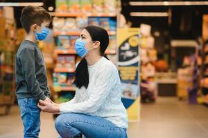 giovane donna e sua ragazzo indossare protettivo viso maschere negozio un' cibo a un' supermercato durante il coronavirus epidemico o influenza scoppio. foto