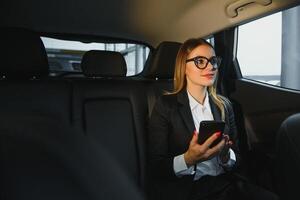 alcuni ordinare di interessante informazione. inteligente donna d'affari si siede a sedile posteriore di il lusso auto con nero interno. foto