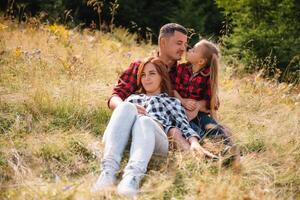 famiglia di tre persone riposo nel il montagne. essi sat giù per riposo, bevanda acqua dopo un' difficile scalata per il montagna. essi siamo stanco ma contento. foto