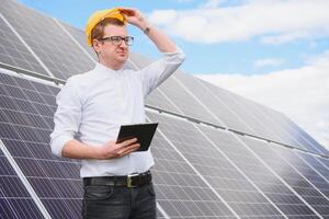 solare energia. giovane attività commerciale uomo nel un' bianca camicia vicino il solare pannelli per energia impianti. foto