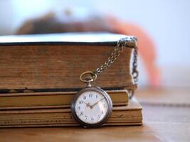 vecchio orologio nel davanti di un' libro foto
