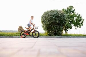 contento ragazzo cavalcata un' bicicletta nel città parco foto