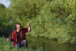 giovane pescatore Pesci vicino il fiume. il concetto di all'aperto attività e pesca foto