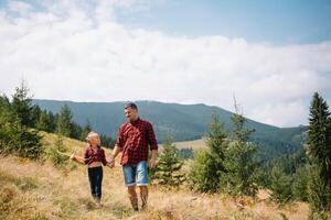 contento padre e poco bambino siamo a piedi nel il montagne. Il padre di giorno. vacanza nel il nazionale parco. foto