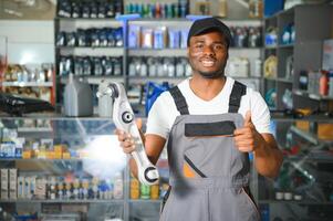 ritratto di un' bello africano venditore nel un auto parti negozio. il concetto di auto riparazione foto