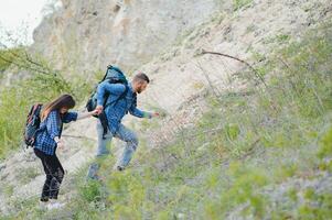 escursionista tipo dà un' mano per il ragazza mentre a piedi nel il montagne, Aiuto e amicizia concetto foto
