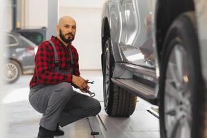 meccanico Lavorando e Tenere chiave inglese di servizio ordine per mantenimento auto a il riparazione negozio foto