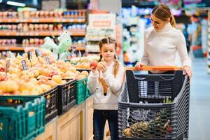 famiglia nel il supermercato. bellissimo giovane mamma e sua poco figlia sorridente e acquisto cibo. il concetto di salutare mangiare. raccogliere foto