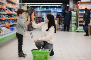 giovane donna e sua ragazzo indossare protettivo viso maschere negozio un' cibo a un' supermercato durante il coronavirus epidemico o influenza scoppio. foto