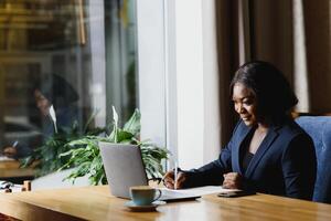 pensieroso nero donna d'affari utilizzando tavoletta computer nel caffè negozio foto