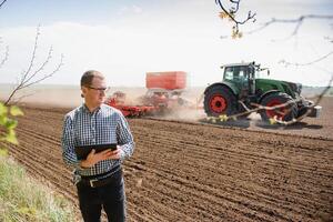 contadino su sfondo di trattore semina campo. opera nel il campo. agricoltura concetto. azienda agricola opera nel il campo nel primavera foto