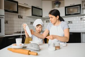 giovane madre e sua poco figlio cottura al forno biscotti insieme a casa cucina foto