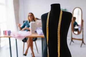 attraente femmina moda progettista è Lavorando nel sua officina. elegante donna nel processi di la creazione di nuovo Abiti collezione foto