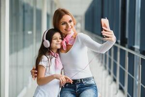mamma con sua figlia a il aeroporto in attesa per un' aereo e assunzione selfie foto