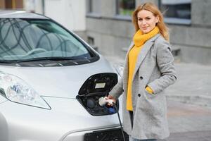 donna ricarica elettro auto a il elettrico gas stazione. foto