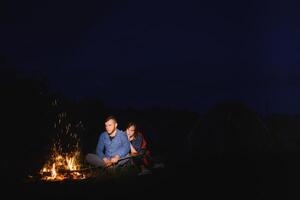 contento romantico coppia i viaggiatori riposo a falò vicino raggiante turista tenda sotto sorprendente notte cielo. il concetto di attivo ricreazione e viaggio con un' tenda foto