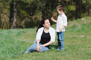 elegante madre e bello figlio avendo divertimento su il natura. contento famiglia concetto. bellezza natura scena con famiglia all'aperto stile di vita. contento famiglia riposo insieme. felicità nel famiglia vita. madri giorno. foto