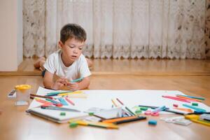 bambini disegno su pavimento su carta. prescolastico ragazzo e ragazza giocare su pavimento con educativo giocattoli - blocchi, treno, Ferrovia, aereo. giocattoli per prescolastico e asilo. bambini a casa o asilo nido foto