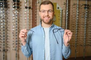 assistenza sanitaria, vista e visione concetto. contento uomo la scelta bicchieri a ottica negozio, selettivo messa a fuoco foto