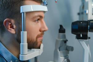 bello giovane uomo è controllo il occhio visione nel moderno oftalmologia clinica. paziente nel oftalmologia clinica foto