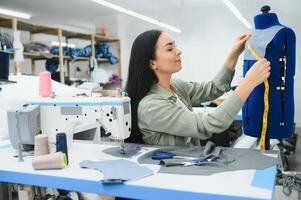 positivo giovane donna cucire con professionale macchina a officina. foto