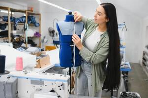 bella giovane donna che cuce vestiti con macchina da cucire. foto