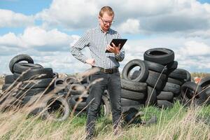 eco-attivista a il discarica di Usato auto pneumatici calcola ambientale danno. natura conservazione concetto foto