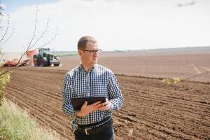 giovane contadino su terreni agricoli con trattore nel sfondo foto