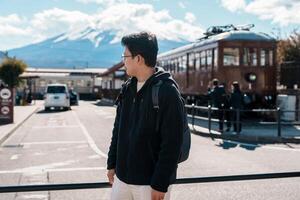 uomo turista con fuji montagna a Kawaguchiko treno stazione, contento viaggiatore giro turistico montare fuji nel yamanashi, Giappone. punto di riferimento per turisti attrazione. Giappone viaggiare, destinazione e vacanza foto