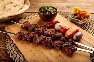 shish kebab o Manzo seekh boti servito nel un' di legno taglio tavola isolato su di legno sfondo lato Visualizza foto