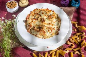 pollo formaggio anacardio noccioline pasta nel un' piatto lato Visualizza su di legno sfondo foto