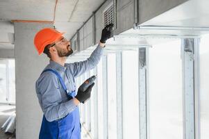 industriale tema. magazzino riscaldamento e raffreddamento sistema installazione di professionale caucasico tecnico. commerciale edificio ventilazione rettangolo canali. aria distribuzione. foto