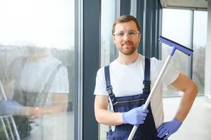 un dipendente di un' professionale pulizia servizio lavaggi il bicchiere di il finestre di il costruzione. vetrina pulizia per negozi e imprese. foto