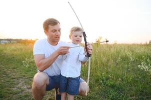 un' padre insegnamento il suo figlio Come per sparare arco. foto