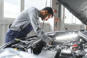 latino ispanico auto meccanico nel uniforme è l'esame un' auto mentre Lavorando nel auto servizio foto