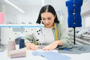 contento femmina sarta Lavorando con cucire macchina a tessile fabbrica. foto