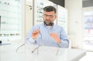 bicchieri dai un'occhiata, anziano visione e anziano uomo a un' consulenza optometria clinica per benessere. felice, Sorridi e vecchio viso con lente, telaio e occhiali scelta nel un' memorizzare per Aiuto ottenere un' prescrizione. foto